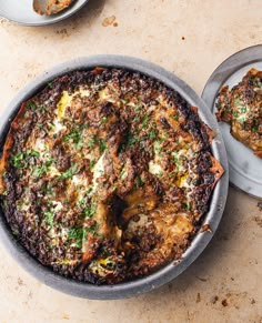 an overhead view of a baked dish on a table with two plates and spoons