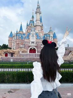 a woman with long hair standing in front of a castle