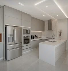 a modern kitchen with stainless steel appliances and white countertops, along with an island in the middle