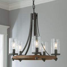 a chandelier with five glass jars hanging from it's center beam in a room