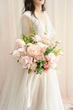 a woman in a white dress holding a bouquet of pink and white flowers on her wedding day