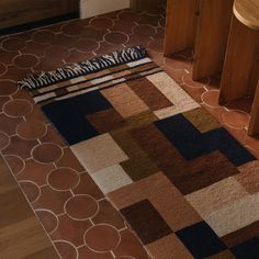 an area rug on the floor next to a table and stools in a room