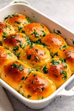 a casserole dish filled with rolls covered in cheese and herbs