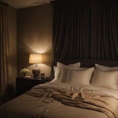 there is a bed with white sheets and pillows on it, next to a lamp