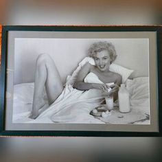 an old photo of a woman laying in bed with her legs crossed and holding a bottle