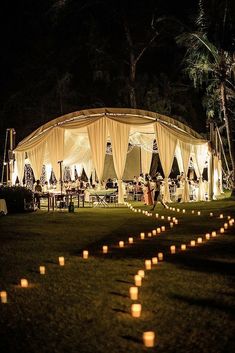 a large tent with candles in the grass