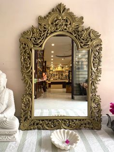 a mirror sitting on top of a table next to a buddha statue