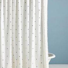 a white shower curtain with black dots on it and a blue wall in the background