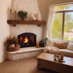 a living room filled with furniture and a fire place next to a large window on top of a hard wood floor