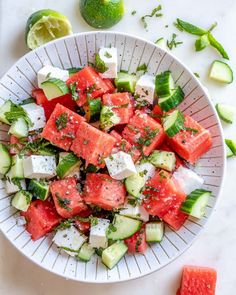 two hands holding a white bowl filled with watermelon and cucumber salad