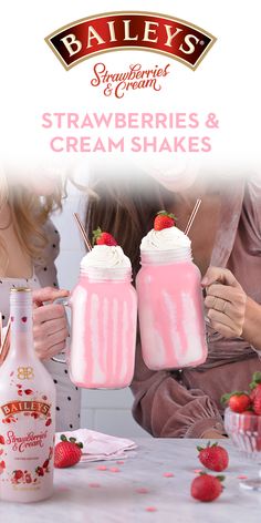 two women holding strawberries and cream shakers in front of a bottle with strawberries on it