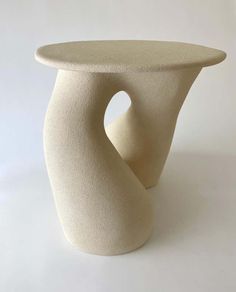 a white vase sitting on top of a table next to a white wall and floor