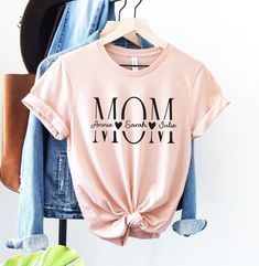 Mom Shirt, Kids Names Shirt, Personalized Mom Shirt, Custom Mom Shirt, Mothers Day Shirt, Mom Birthday Gift, Gift for Mom, Mama Shirt HOW TO PLACE YOUR ORDER * Choose your t-shirt color * Choose your size * Choose your design&text color * PLEASE make sure all your order's steps PRODUCT DESCRIPTION T-shirt feels soft and light, with just the right amount of stretch. It's comfortable and the unisex cut is flattering for both men and women. * Solid colors are 100% combed and ring-spun cotton * Ash Mom Tshirt Ideas Design, Name Print Top For Birthday And Mother's Day, Pink Letter Print Shirt For Birthday Gift, Pink Shirt With Letter Print For Birthday Gift, Personalized Pink T-shirt For Mother's Day, Cotton Letter Print Shirt For Birthday Gift, Letter Print Tops For Mother's Day, Birthday Shirt For Mother's Day With Crew Neck, Cotton T-shirt For Mother's Day Family Events