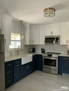 a kitchen with white and blue cabinets, stainless steel appliances and an island countertop