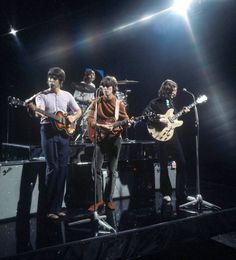 the beatles performing on stage with their guitars