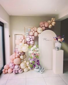 balloons and flowers are arranged on the floor in front of a white wall with a doorway