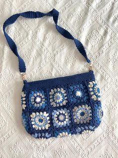 a blue crocheted purse sitting on top of a bed