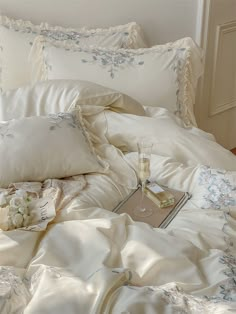 an unmade bed with white sheets and blue flowers on the comforter is shown