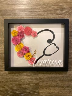 a frame with flowers in the shape of a stethoscope and name on it