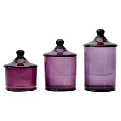 three purple glass jars with lids on white background