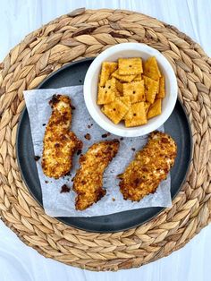 some food is on a black plate and next to a bowl of cracker chips