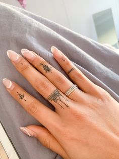 a woman's hand with two tattoos on her fingers, and one has a ring in the middle