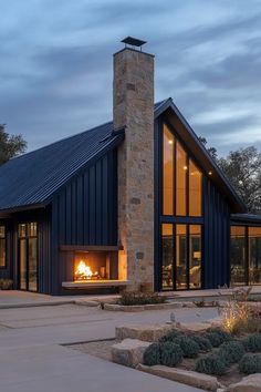 a modern house with a fireplace in the center and large windows on each side, surrounded by stone steps