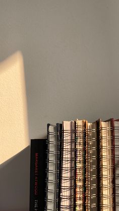 a stack of books sitting on top of a wooden table next to a white wall