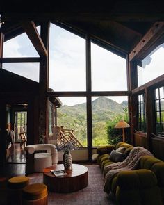 a living room filled with lots of furniture and large windows overlooking the mountain range in the distance