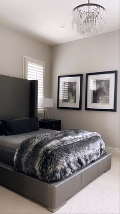 a bedroom with a large bed and two pictures on the wall above it, along with a chandelier