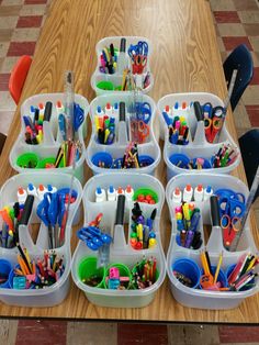 several plastic containers filled with school supplies on top of a wooden table