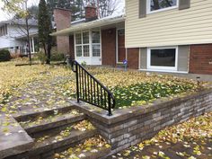 a house with fall leaves on the ground and stairs leading up to it's front door