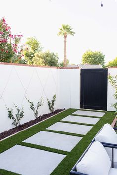 an outdoor patio with grass and stepping stones in the middle, surrounded by palm trees