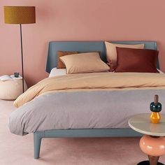 a bedroom with pink walls and a blue bed frame in the middle, along with two end tables on either side