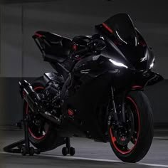 a black motorcycle with red rims parked in a parking garage next to a building