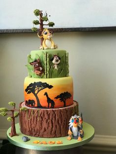 a three tiered cake decorated with animals and trees