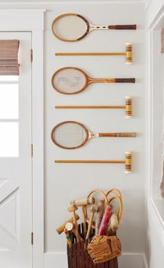 there are many tennis rackets hanging on the wall in this room, along with other sports related items