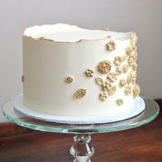 a white and gold decorated cake sitting on top of a glass plate