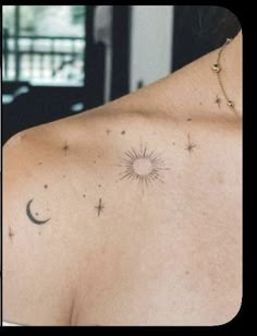 the back of a woman's shoulder with stars and moon tattoos on it