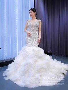 a woman in a white wedding dress standing next to a blue curtain with lights on it