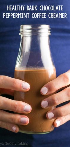 a woman holding a glass jar filled with brown liquid and almonds on her hands