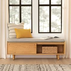 a wooden bench sitting next to a window in front of a white wall with black windows