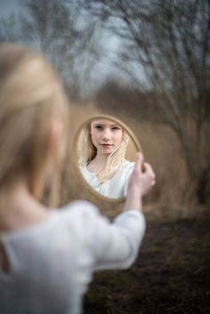 a woman is looking at herself in the mirror