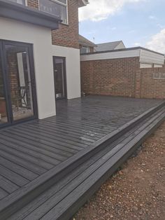 a wooden deck in front of a house with sliding glass doors on the outside side