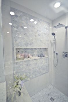 a white tiled bathroom with shower head and hand held shower faucet in the corner