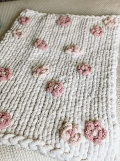 a crocheted blanket with pink flowers on it