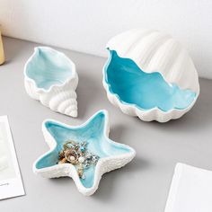 three starfish shaped dishes sitting on top of a table next to a book and vase