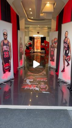 an indoor basketball court with red and black drapes on the walls, two men's jerseys hanging in front of them