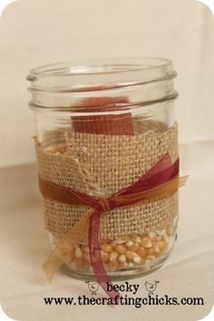 a glass jar filled with corn kernels on top of a white cloth covered table