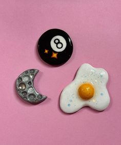 two eggs and an egg shell are on a pink surface next to a black ball